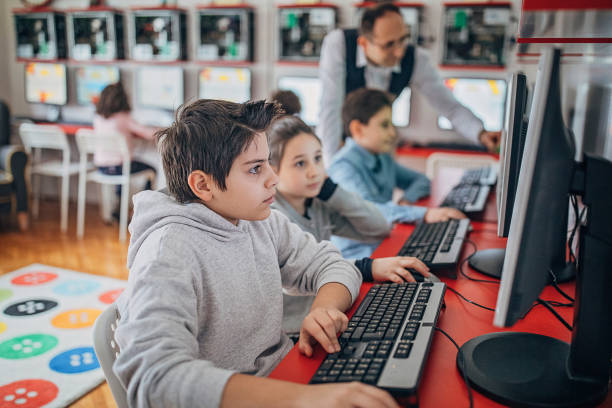컴퓨터를 사용하여 젊은 미취학 연령의 학생들을 돕는 교사 - computer lab child internet development 뉴스 사진 이미지