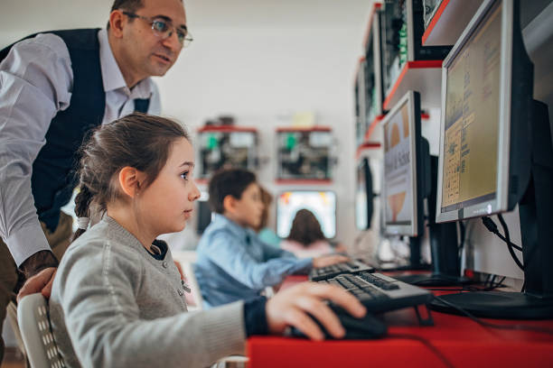 컴퓨터를 사용하여 유치원 연령의 학생을 돕는 교사 - computer lab child internet development 뉴스 사진 이미지