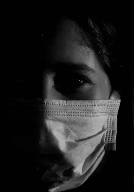 Photo of portrait of girl in shadow with mask in black and white