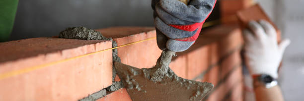 builder with spatula to remove excess cement - protective workwear bricklayer manual worker construction imagens e fotografias de stock