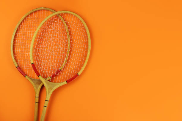 istock badminton rackets on a bright orange background. Copy space for your text 1253417474