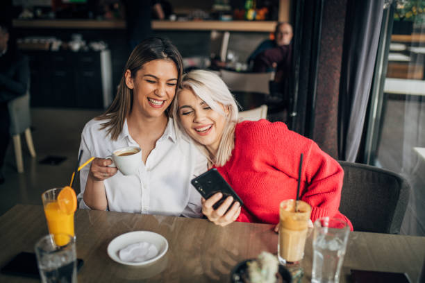 istock Two girlfriends sitting in the coffee shop and using mobile phone 1253420299