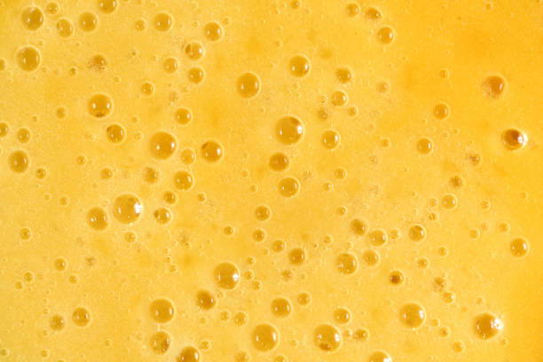 Full frame Yellow foam texture with bubbles of mango and banana fruit smoothie with juice stock photo