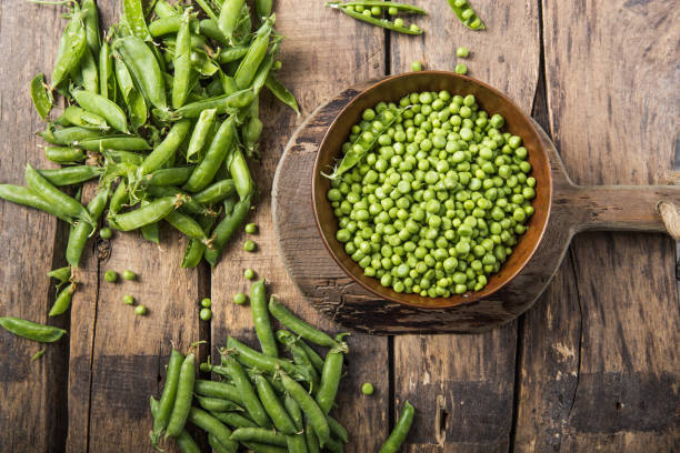 istock Young fresh green peas on wooden  table viewed from above 1253424584