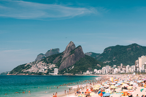 Large group of people at Ipanema Beach and the Two Brother Mountain in Rio de Janeiro, Brazil.