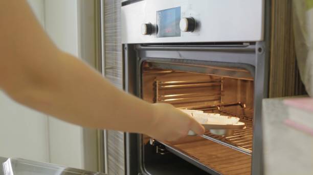 istock Woman chief put cupcake in kitchen oven 1253426230