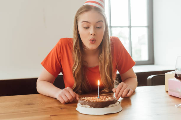 おいしいバースデーケーキにろうそくを吹き消す若い女性 - cake birthday candle blowing ストックフォトと画像