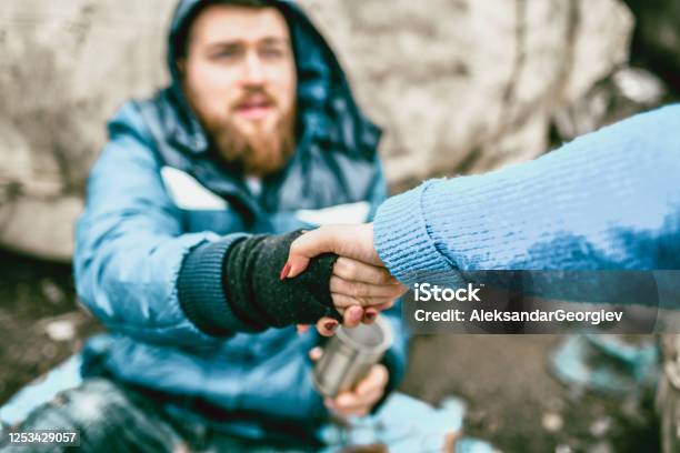 Female Offering Support For Homeless Male On Street Stock Photo - Download Image Now