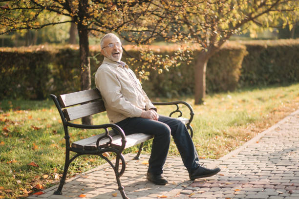 istock Old gray-haired man rest on the bench in autumn park 1253429226