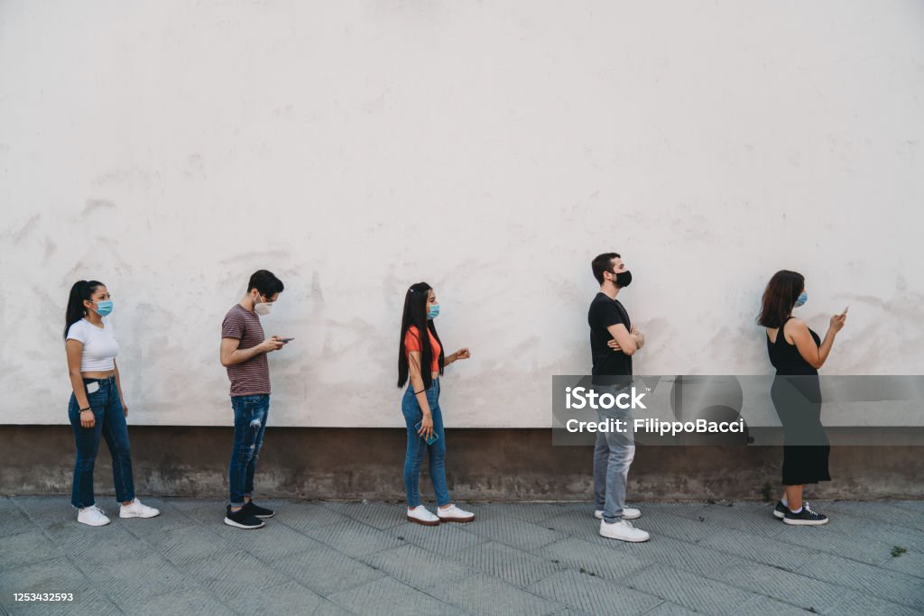 People waiting in line to enter in a store - Social distancing concept People waiting in line to enter in a store - Social distancing concept. During the coronavirus Covid-19 pandemic, the entrances to the shops are quoted. Waiting In Line Stock Photo
