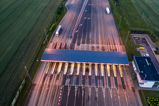 Car traffic transportation on multiple lanes highway road and toll collection gate, drone aerial top view at Night. Commuter transport, city life concept.A2 Poland Lodz