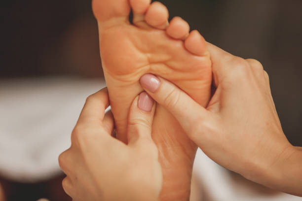 Close up shot of massage therapist's hands applying pressure points onto her client's foot during reflexology massage at the spa.