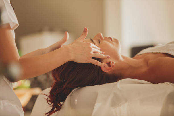 mujer disfrutando de un masaje facial en el spa de belleza - pampering massaging indoors adult fotografías e imágenes de stock