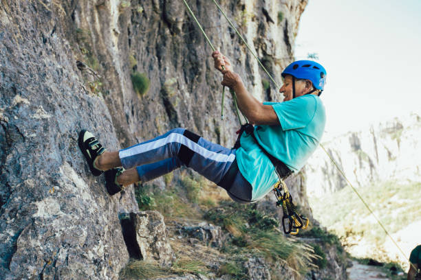 istock Senior man with a rope climbing on the rock. 1253439433