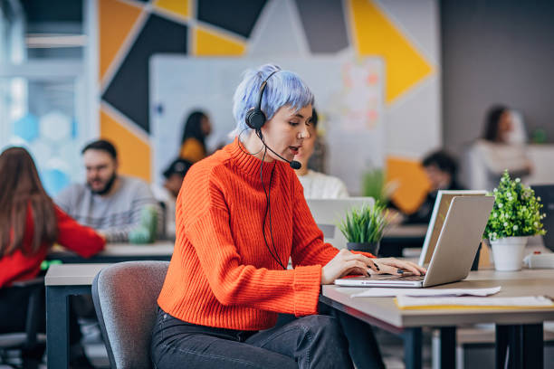 istock Woman using laptop and headset in big modern office 1253439723
