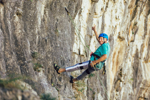 istock Senior man with a rope climbing on the rock. 1253441279