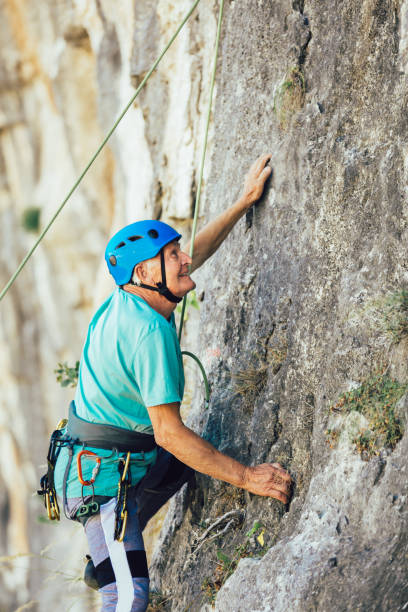 senior mann mit einem seil klettern auf den felsen. - conquering adversity wilderness area aspirations achievement stock-fotos und bilder