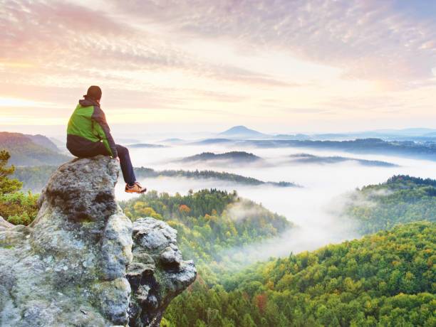 istock Hiker Man Take A Rest On Mountain Peak. Man Sit On Sharp Summit And Enjoy Spectacular View. 1253445990