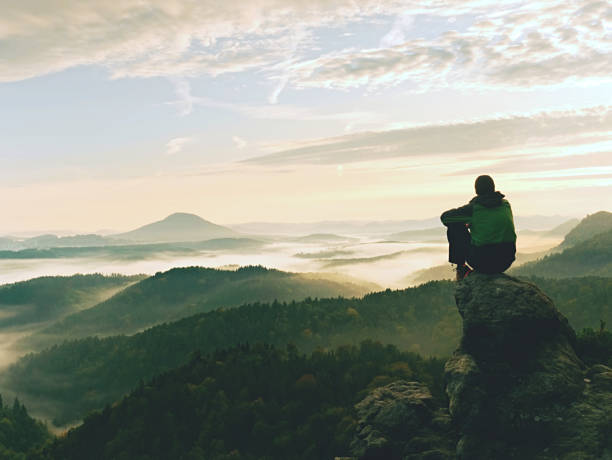 istock Mountain Peak. Man Sit On Sharp Summit And Enjoy Spectacular View. Bright Morning Sun Shining In Sky 1253445997