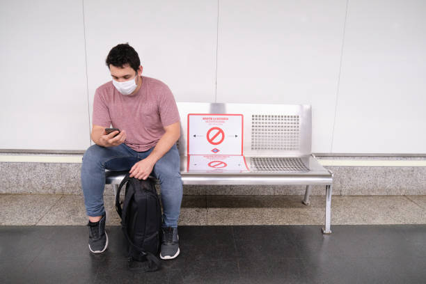 istock Young caucasian man wearing mask checking his smartphone while is waiting for the train to come 1253450597