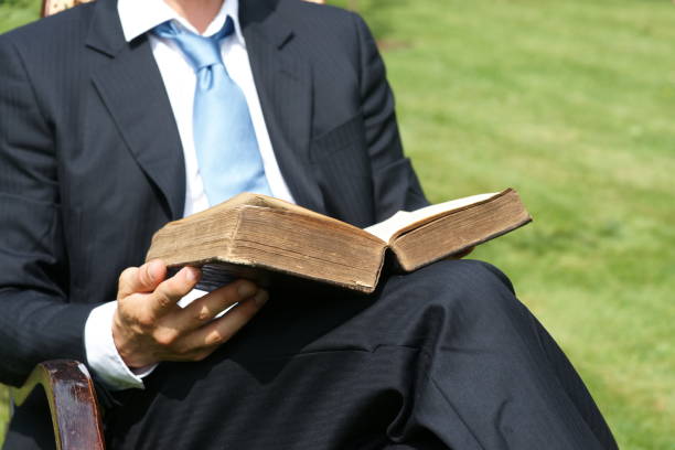 Businessman reading an old book and relaxing in the garden - Close-Up Man sits in chair and reads antique book - bible or law book or dictionary mormonism stock pictures, royalty-free photos & images