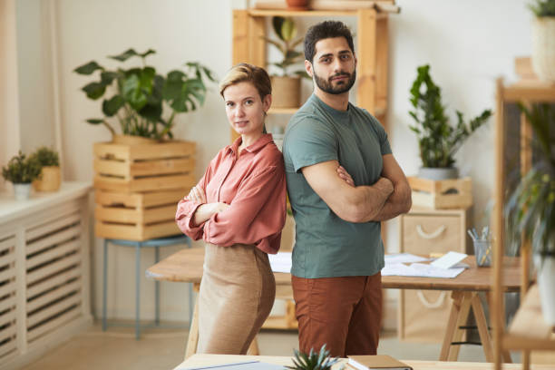 istock Man and Woman Standing Back to Back in Office 1253456196