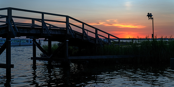 Bridge and promenade with majestic cloudscape at sunset. Location: Lake Steinhuder Meer, Lower Saxony, Germany.