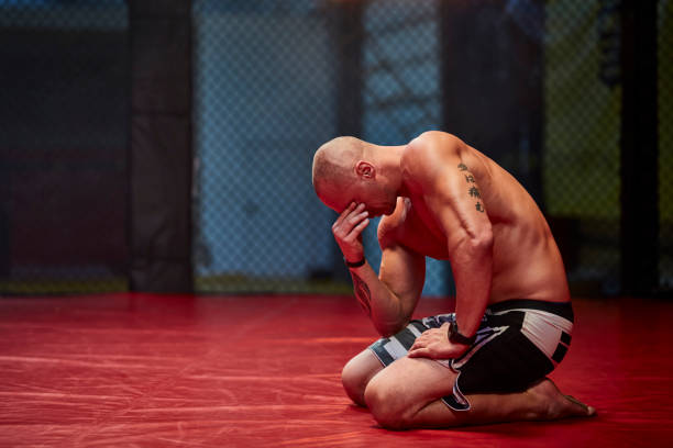 Disappointed athlete after lost fight Man on a fighting ring. Defeated and sad mixed martial arts photos stock pictures, royalty-free photos & images