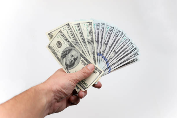istock Hundred dollar bills in his hand on a white background. 1253459979