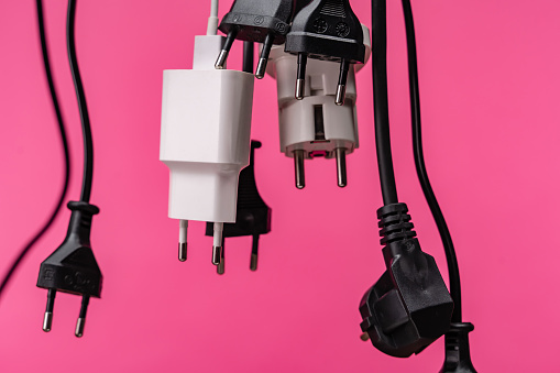 Crowded  white extension cord with many plugs on pink background. The scene is situated in controlled studio environment in front of pink background. Photo is taken with SONY AIII camera