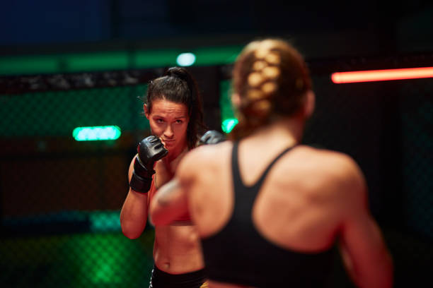 istock Female MMA fighters throw punches in octagon. Close up 1253460404