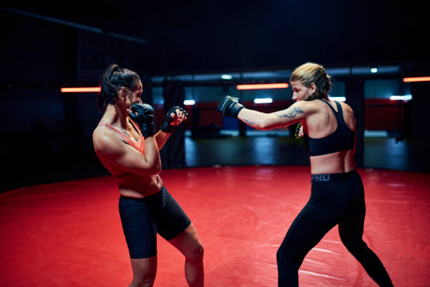 istock Female MMA fighters throw punches in octagon 1253460431