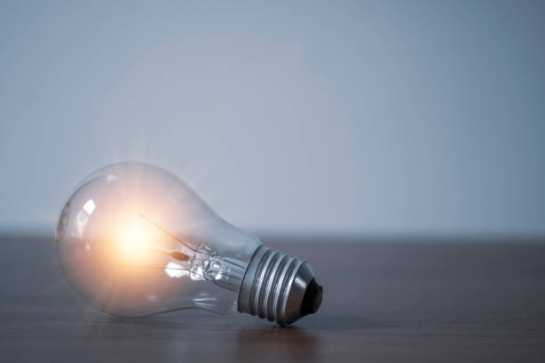 istock Closeup of lightbulb with orange glowing on the table. Creative idea concept. 1253460493