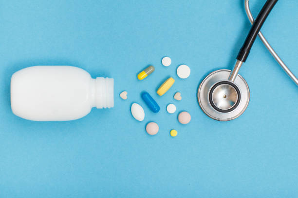 istock White bottle with different pills and phonendoscope on blue background 1253461706