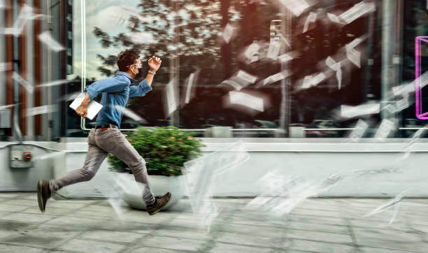 The Man hurry running pass many papers are blowing around urban. stock photo