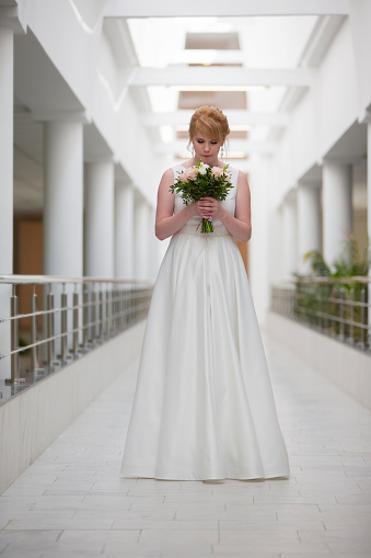 Beautiful bride with a bouquet in the hallway. The girl in the registry office.