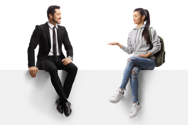 istock Female student talking to a businessman and sitting on a blank panel 1253464041