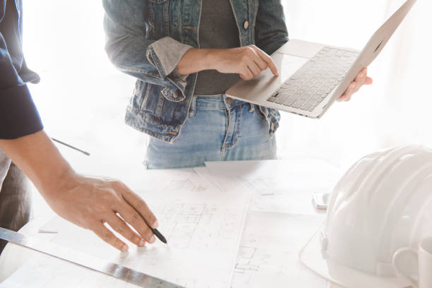 istock Engineer or architect working and discussing with blueprint and holding pencil and laptop on hand in office. concept of teamwork and partnership. 1253465518