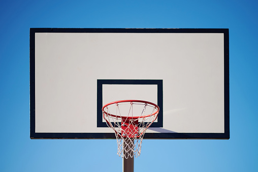 White basketball board with ring on blue sky background