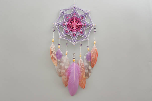 Yarn mandala with feathers and amethyst beads on grey background