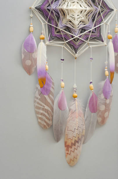 istock Yarn mandala with feathers and amethyst beads on grey background 1253466305