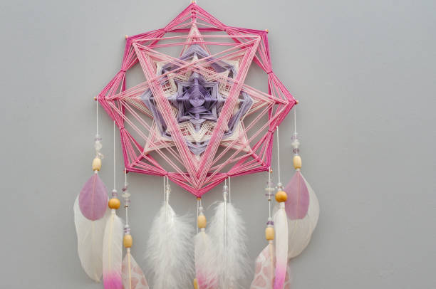 istock Yarn mandala with feathers and amethyst beads on grey background 1253466822