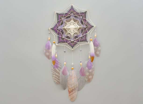 istock Yarn mandala with feathers and amethyst beads on grey background 1253466901