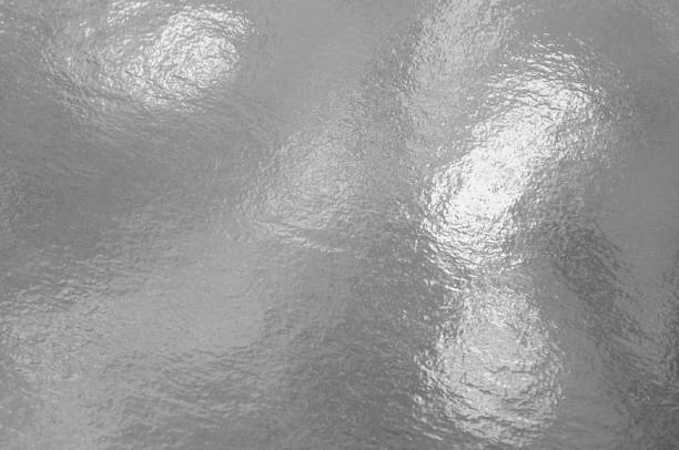 Silver foil texture background with highlights and uneven surface
