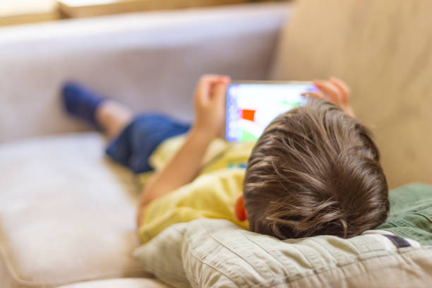istock Little cute boy playing games on a tablet and watching cartoons. 1253470954