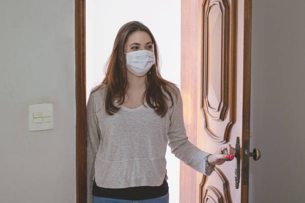 istock Woman entering at home wearing protective face mask. 1253471449