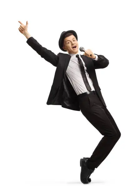 Young showman in a suit dancing and singing on a microphone isolated on white background