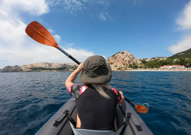 Young woman sea kayaking in the ocean, back view, GoPro.