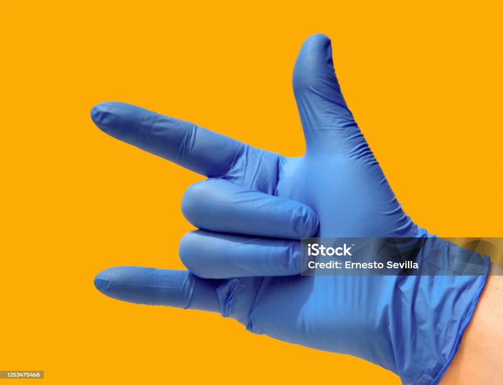 Closed hand with open thumb, index and little finger a blue glove and yellow background. Heavy metal concept. Analyzing Stock Photo