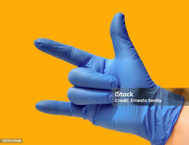 Closed Hand With Open Thumb Index And Little Finger A Blue Glove And Yellow Background Heavy Metal Concept Stock Photo - Download Image Now